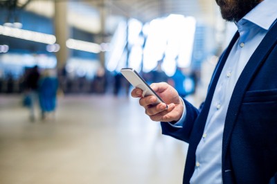 Geschäftsmann mit Smartphone am Bahnhof